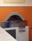 A milano fired oven enclosed by a orange brick wall design.