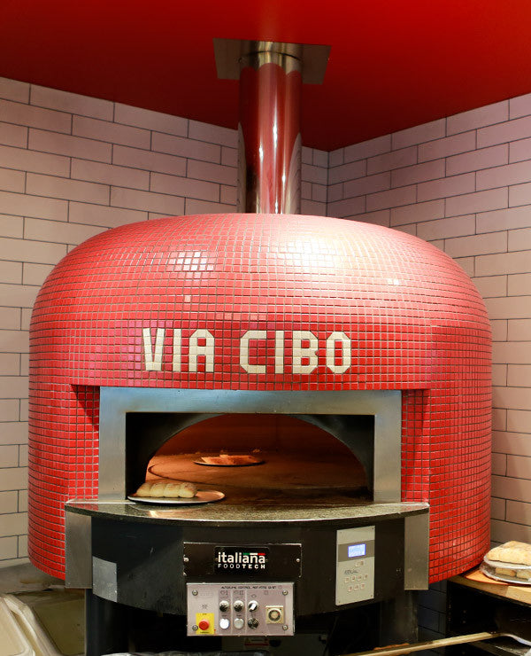 A bright red Napoli fired oven with a custom branded tiling for Via Cibo.