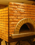 an enclosed Milano fired oven with a custom gold brick tiling design.