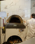 Milano fired oven enclosed within a white marbled wall.